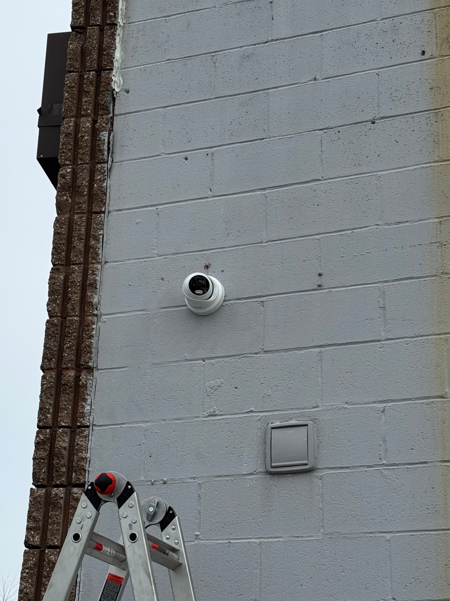 Commercial exterior turret dome camera mounted on cinder block wall